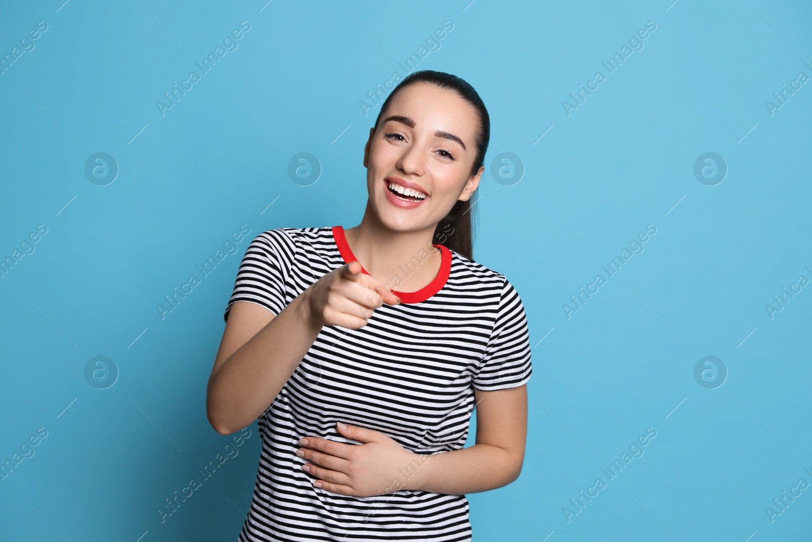 Photo of Beautiful young woman laughing on light blue background. Funny joke