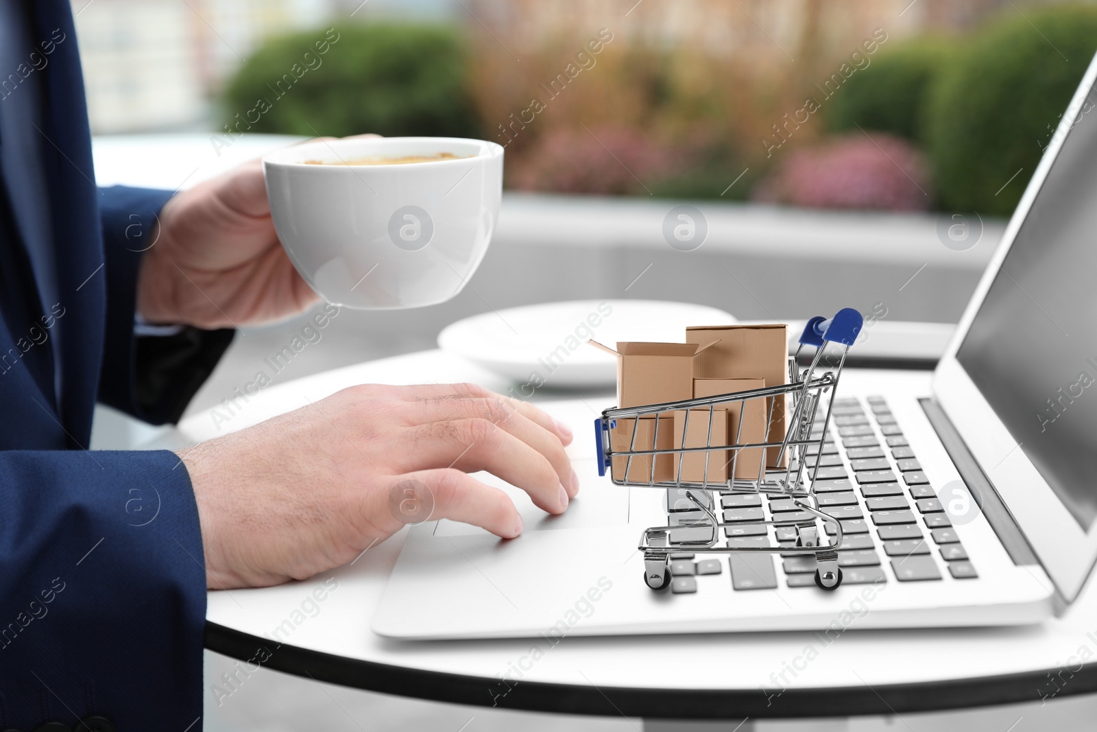 Image of Man shopping online using laptop, small cart with boxes on computer