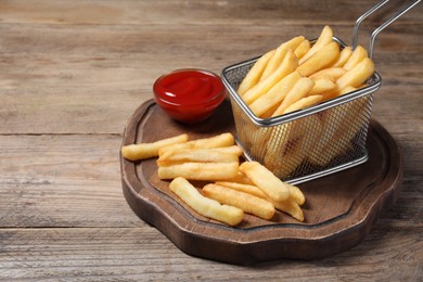 Tasty French fries served with ketchup on wooden table. Space for text