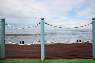 Picturesque view of sea with waves behind pier fence