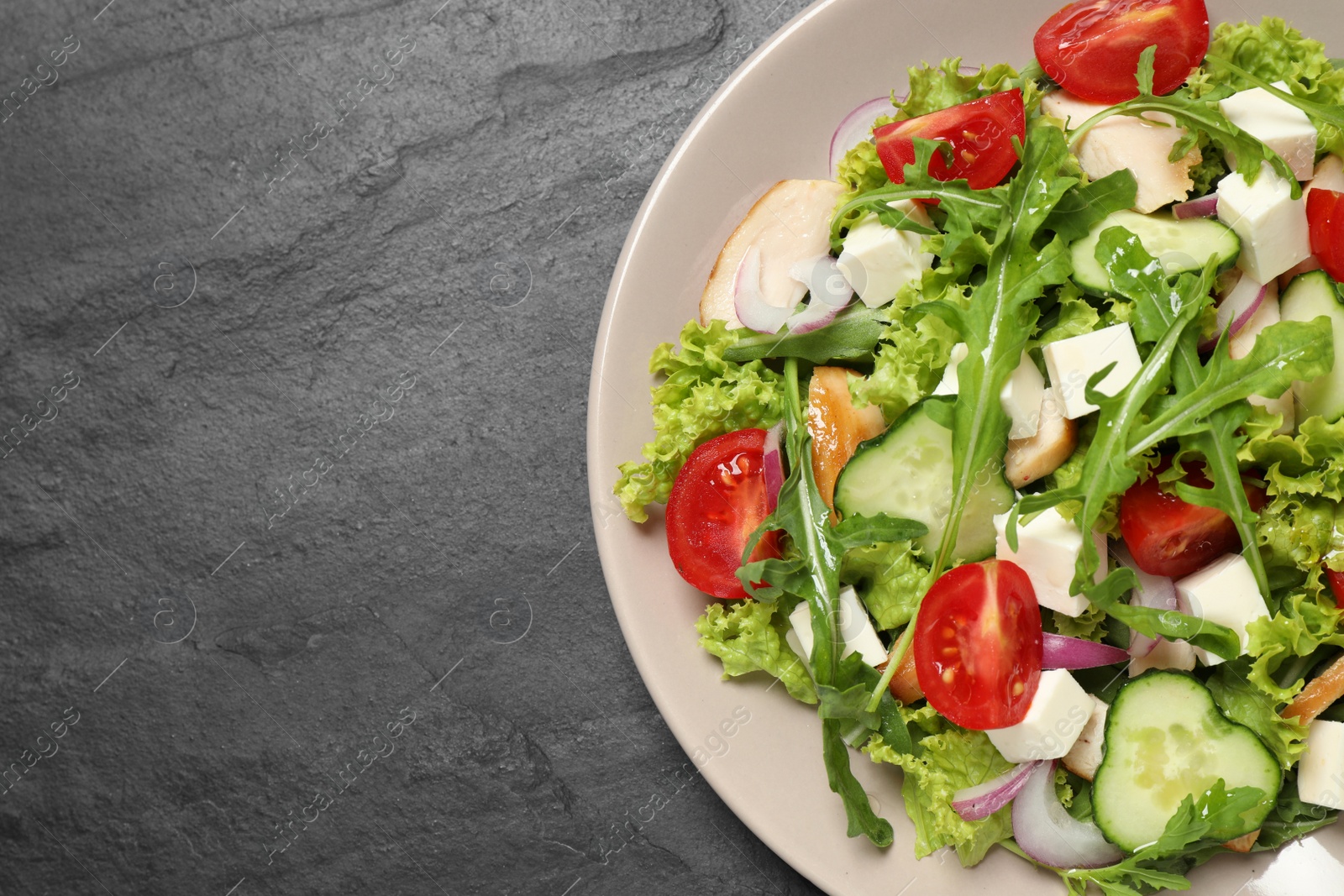 Photo of Delicious salad with meat, arugula and vegetables on black table, top view. Space for text