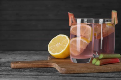 Photo of Tasty rhubarb cocktail with lemon on wooden table, space for text