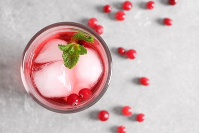 Photo of Tasty cranberry juice with ice cubes in glass and fresh berries on light grey table, top view
