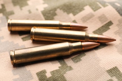 Photo of Military bullets on pixel Ukrainian camouflage, closeup