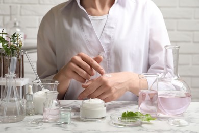 Photo of Scientist testing cosmetic product at white marble table in laboratory, closeup
