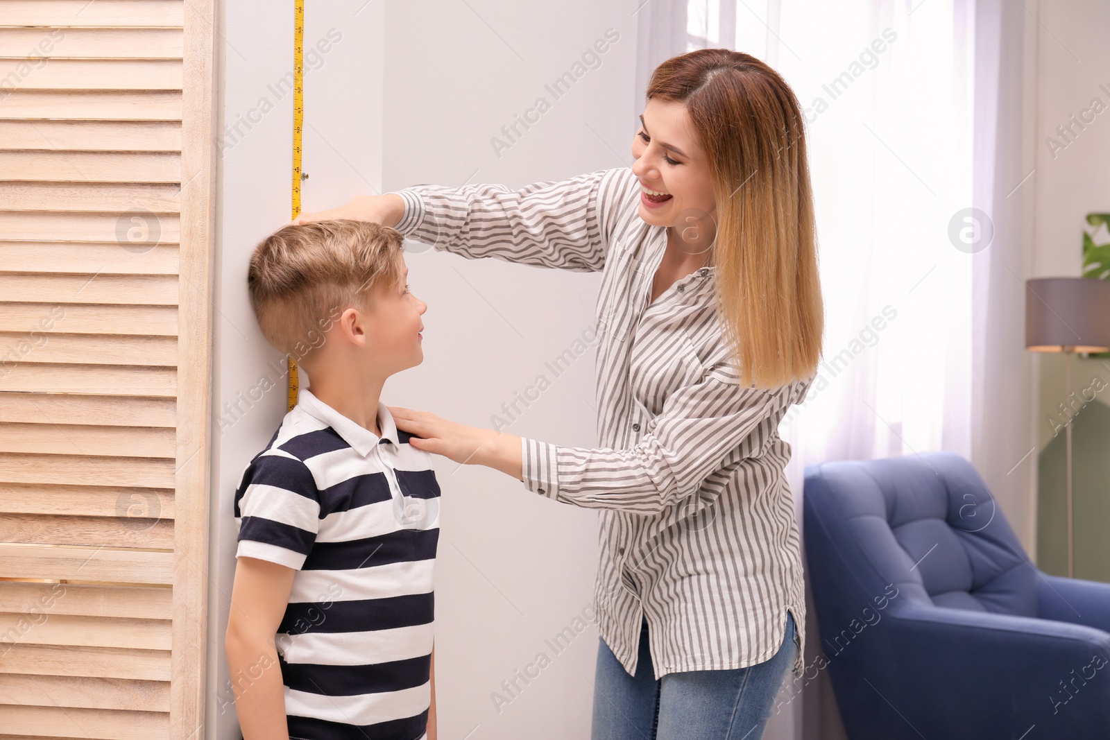 Photo of Young woman measuring her son's height at home