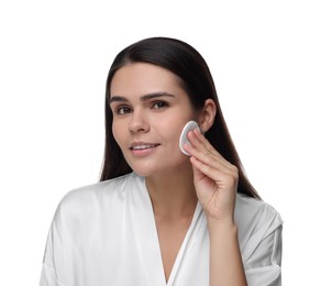 Young woman cleaning her face with cotton pad on white background