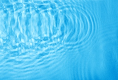 Concentric waves on blue water surface after falling drops, top view