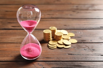 Photo of Hourglass and coins on table. Time management