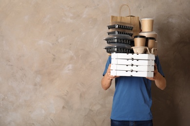 Courier with stack of orders on beige background, space for text. Food delivery service