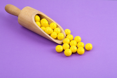 Delicious lemon chewing gums and scoop on purple background