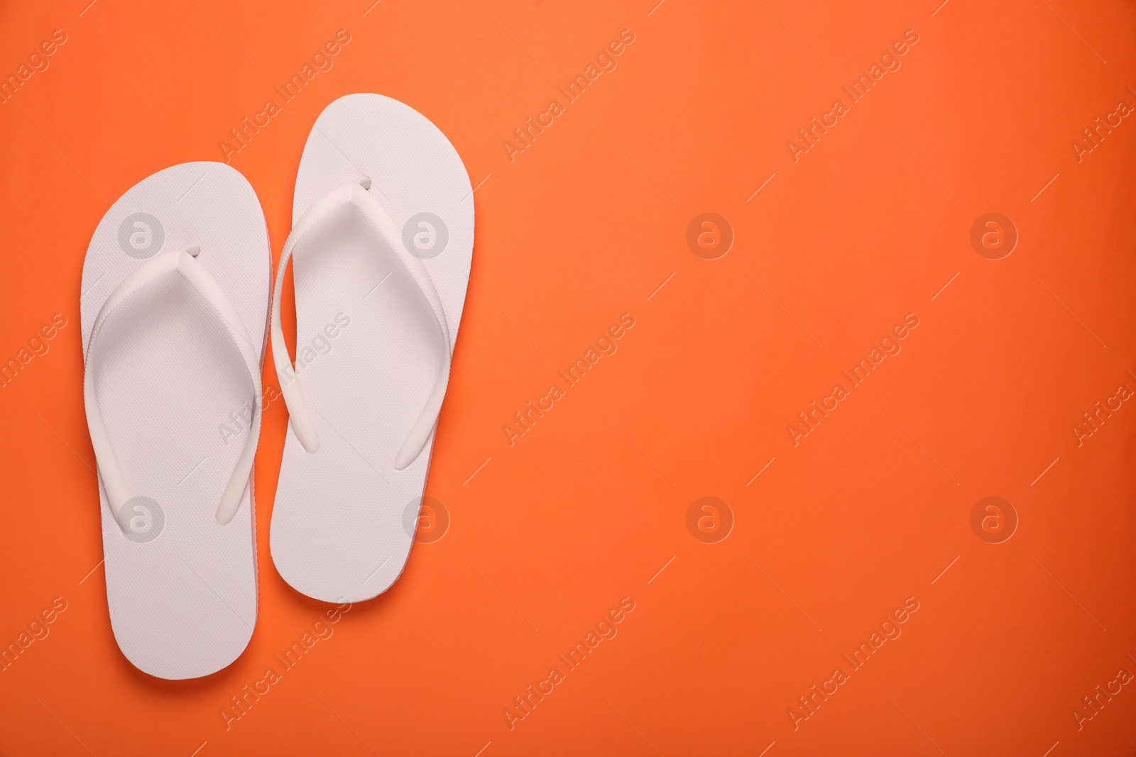 Photo of Stylish white flip flops on orange background, top view. Space for text