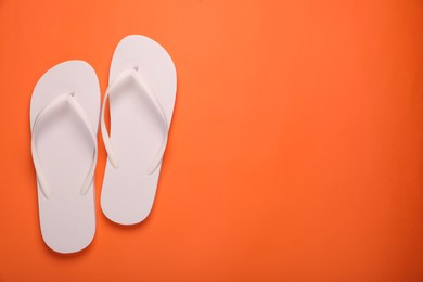 Photo of Stylish white flip flops on orange background, top view. Space for text