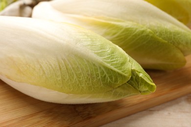 Photo of Board with raw ripe chicories on table, closeup