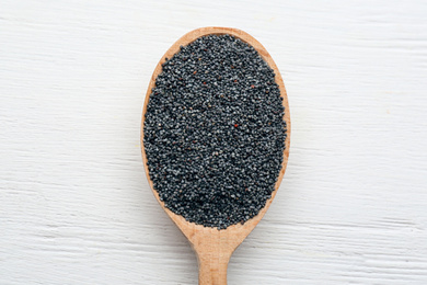 Poppy seeds in spoon on white wooden table, top view