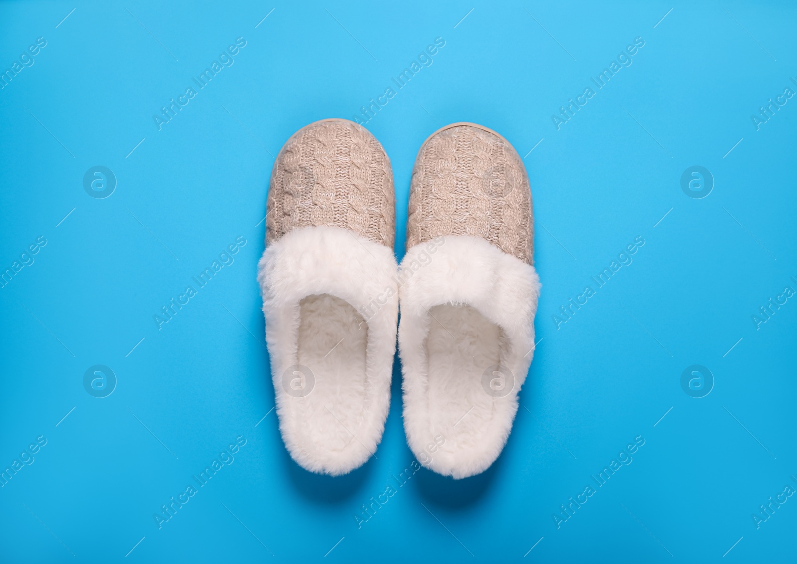 Photo of Pair of beautiful soft slippers on light blue background, top view