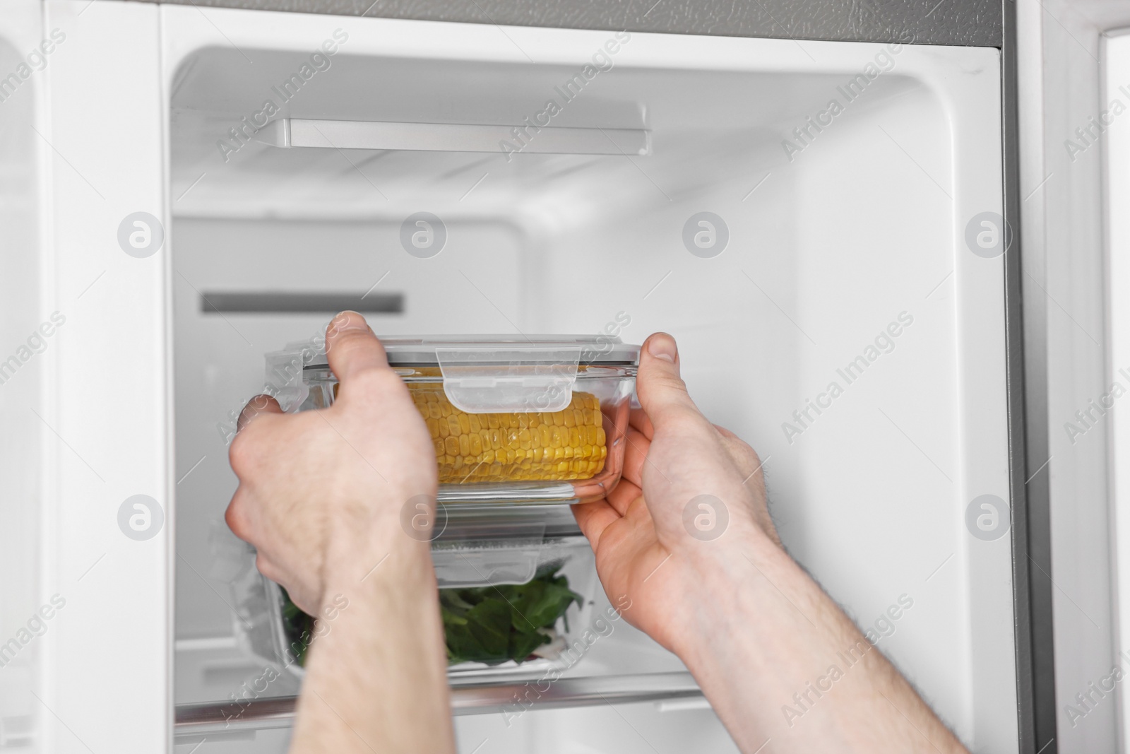 Photo of Man taking container with corn out of refrigerator, closeup