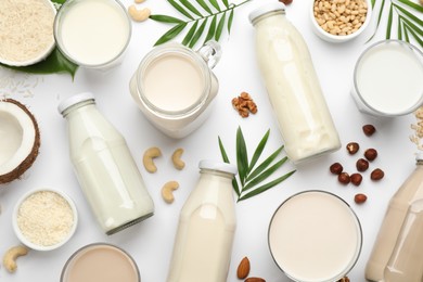 Different vegan milks and ingredients on white background, flat lay
