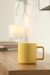 Photo of Yellow mug on wooden table indoors. Mockup for design