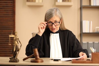 Photo of Judge in court dress working at table indoors