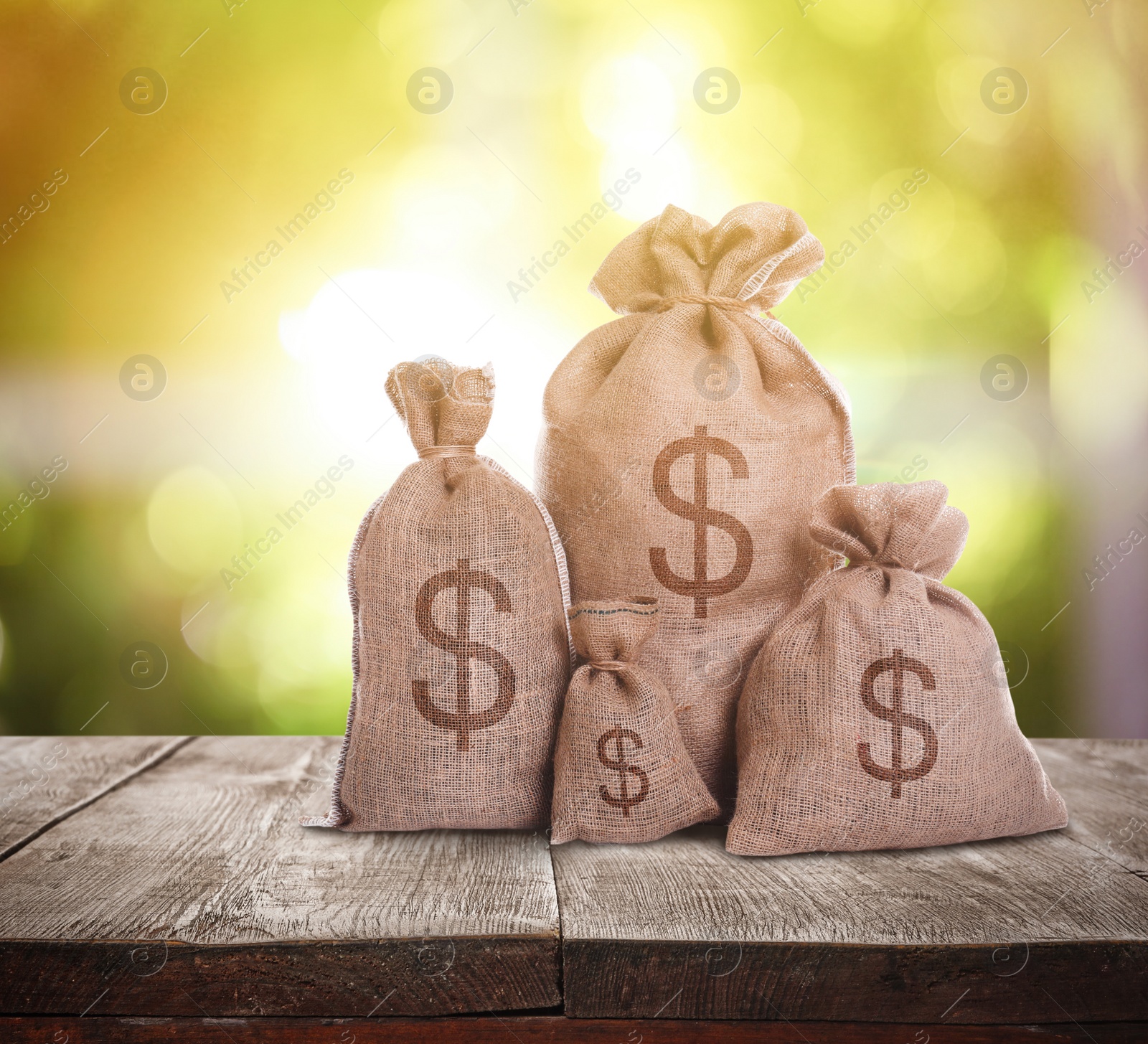 Image of Burlap bags with dollar signs on wooden table indoors