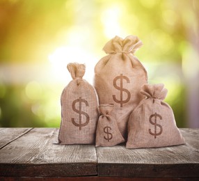 Image of Burlap bags with dollar signs on wooden table indoors