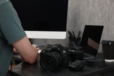 Photographer working on computer at dark table with camera, closeup