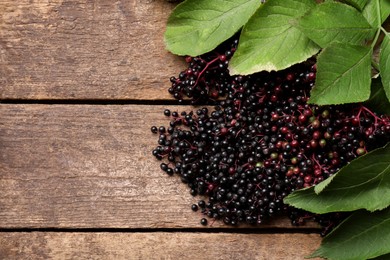 Photo of Pile of tasty elderberries (Sambucus) on wooden table, top view. Space for text