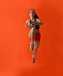 Photo of Athletic young woman running on red background