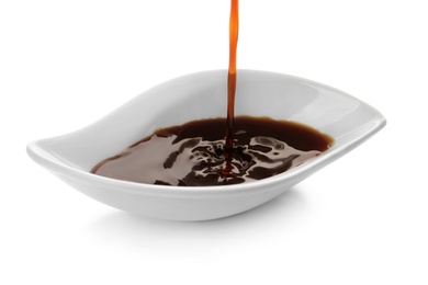 Pouring tasty soy sauce into bowl isolated on white