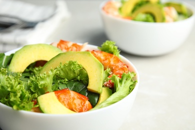 Delicious avocado salad with shrimps in bowl on table, closeup