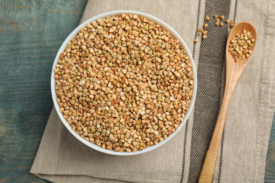 Photo of Uncooked green buckwheat grains on light blue wooden table, flat lay