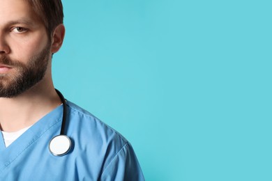 Photo of Doctor or medical assistant (male nurse) in uniform with stethoscope on turquoise background, closeup. Space for text