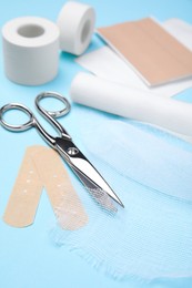 Photo of White bandage and medical supplies on light blue background, closeup