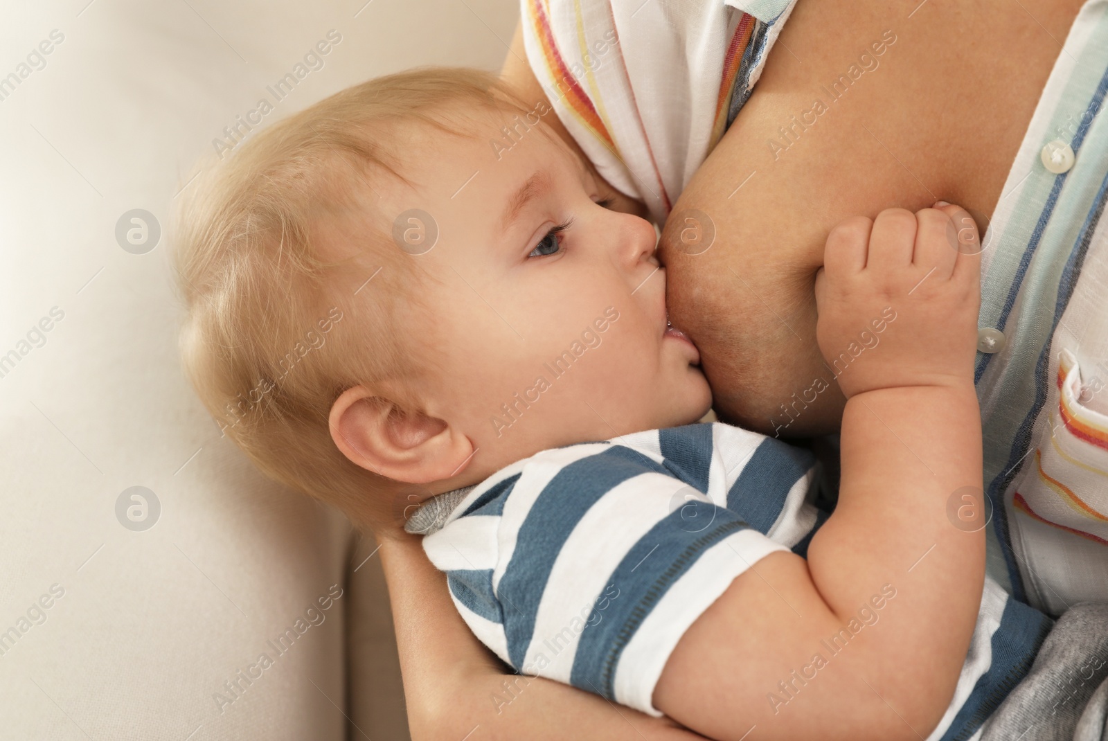 Photo of Woman breastfeeding her little baby at home, closeup