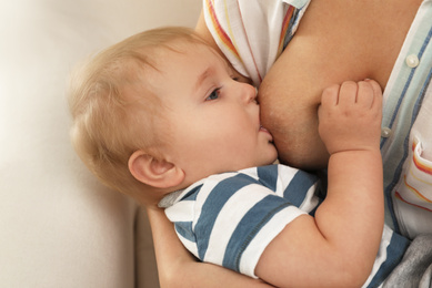 Woman breastfeeding her little baby at home, closeup