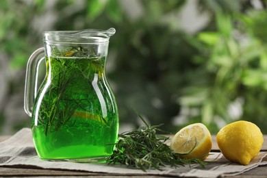 Jug of refreshing tarragon drink with lemon on table, space for text