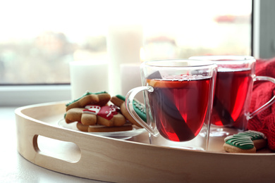 Photo of Cups of delicious mulled wine and cookies on window sill indoors, closeup. Winter drink