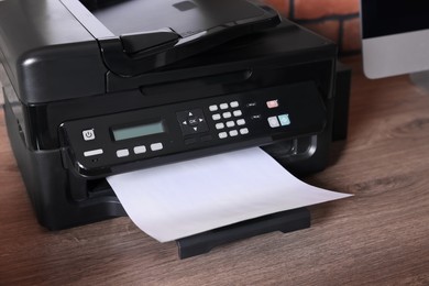 Photo of Modern printer with paper on wooden desk at home, closeup
