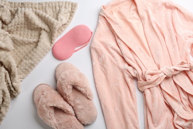 Photo of Composition with pink fluffy slippers and robe on white background, flat lay. Comfortable home outfit