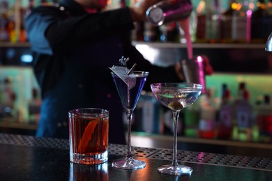 Photo of Bartender making fresh alcoholic cocktail at counter in bar, selective focus