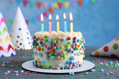 Cute bento cake with tasty cream and burning candles on light blue wooden table