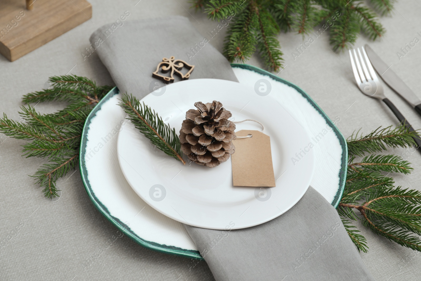 Photo of Festive place setting with beautiful dishware, cutlery and cone for Christmas dinner on grey table
