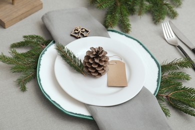 Festive place setting with beautiful dishware, cutlery and cone for Christmas dinner on grey table