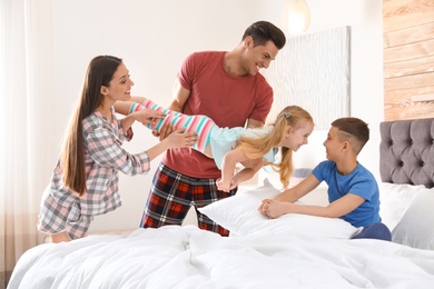 Photo of Happy young family with children having fun in bedroom