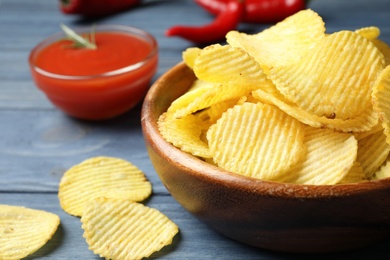 Delicious crispy potato chips in bowl on table, closeup with space for text