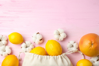 Photo of Cotton eco bag with citrus fruits on pink wooden table, flat lay. Space for text