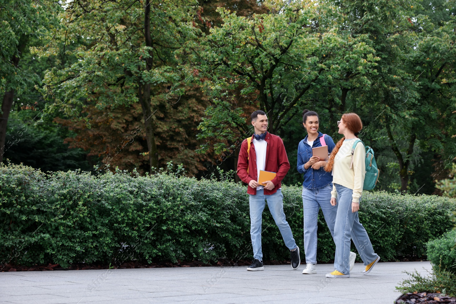 Photo of Happy young students walking together in park