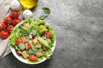 Photo of Delicious salad with chicken, cheese and vegetables served on grey table, flat lay. Space for text