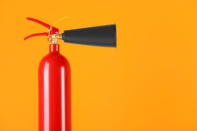 Photo of Fire extinguisher on orange background, closeup with space for text